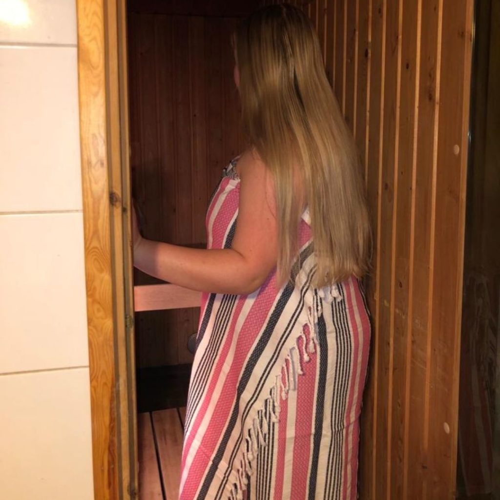 Nainen kävelee saunaan hamam-pyyhe ympärillään