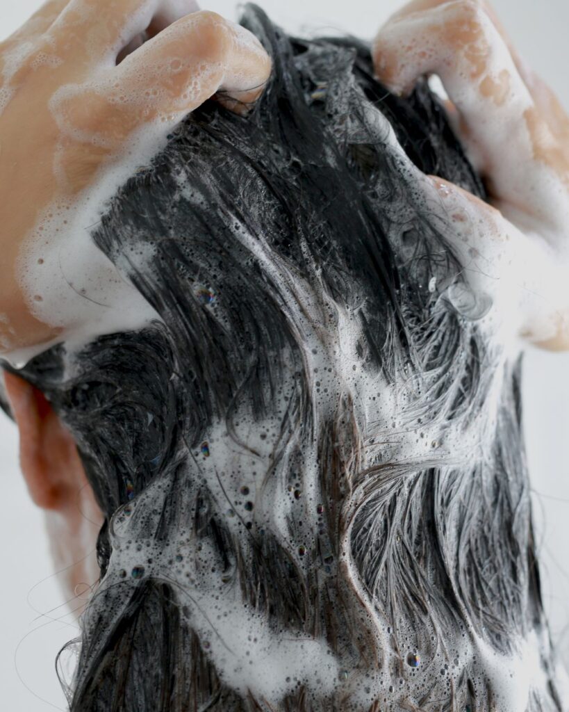 Kädet hierovat shampoovaahtoa päänahkaan
