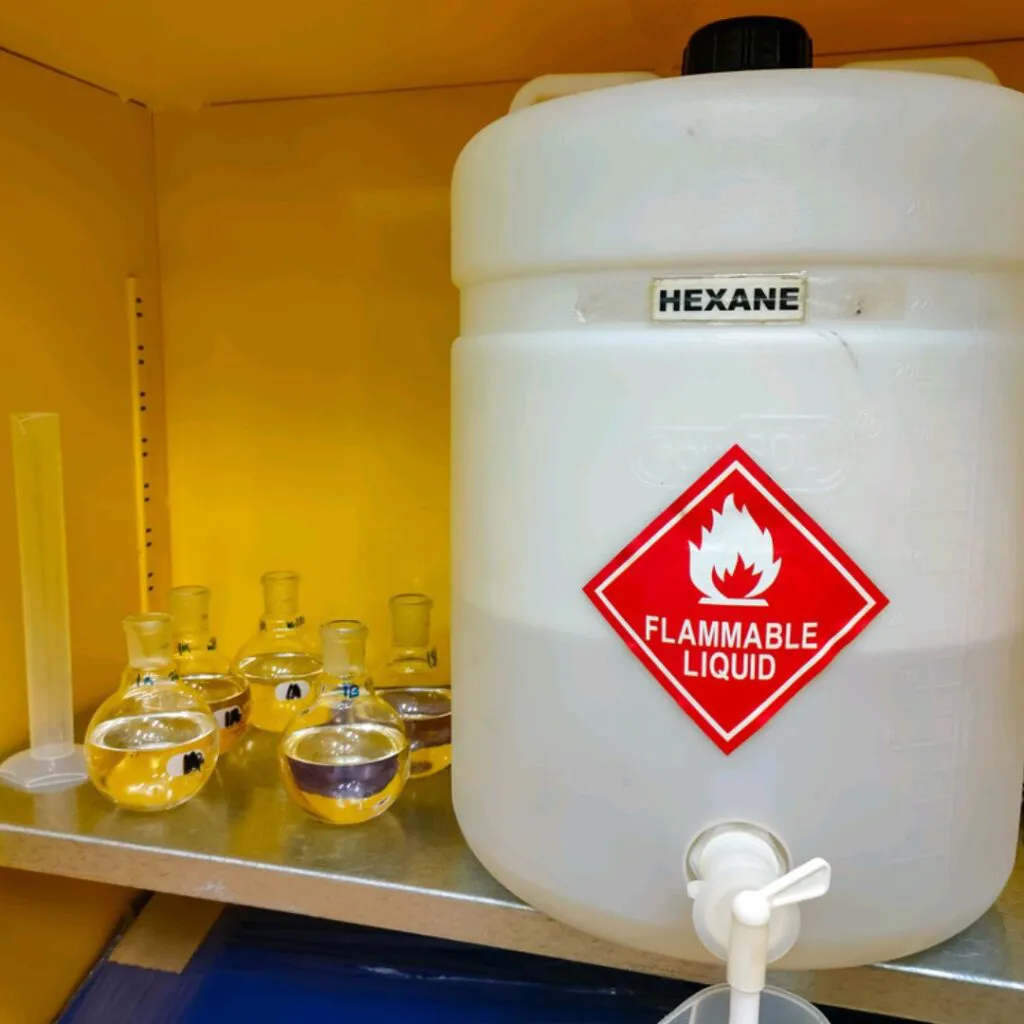 Öljyn käsittely heksaanilla, suuri heksaanitonkka ja pienempiä pulloja, joissa käsiteltyä öljyä