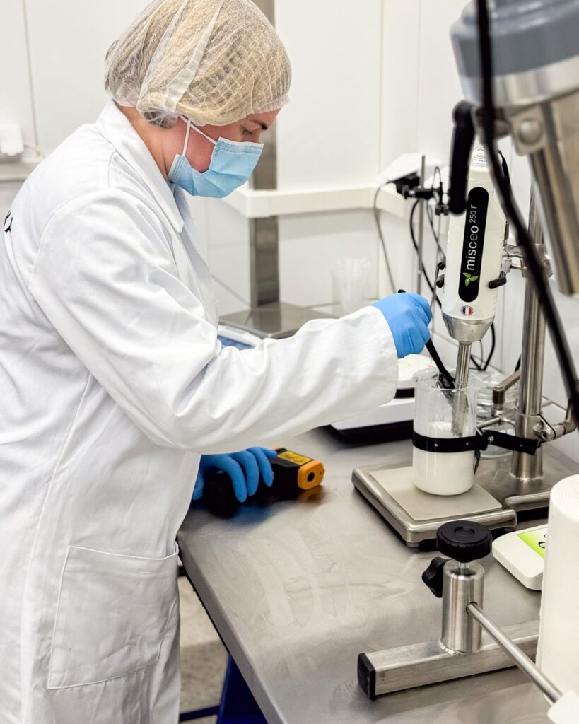Veera Perniön kosmetiikkalaboratoriossa mittaamassa ja sekoittamassa voidetta laboratoriolaitteilla